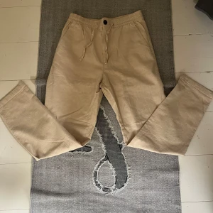 Beiga linnebyxor Selected Homme  - Snygga beiga linnebyxor från Selected Homme i storlek S. Byxorna har elastisk midja med snörning och raka ben. Perfekta för en chill och stilren look, tillverkade i ett luftigt linnematerial som passar grymt under varmare dagar. OBS storlek är oklart vid intresse kan jag mäta dom! 