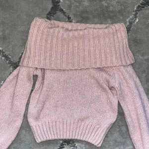 Rosa offshoulder stickad tröja - Superfin rosa stickad tröja med bred offshoulder-krage. Tröjan har lång ärm och ribbade muddar vid ärmslut och nederkant. Perfekt för dig som gillar en mysig och trendig look med lite extra attityd. har bara använt ett par ggr