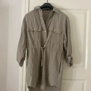 Beige skjortklänning från Zara XS - Stilren  grön jacka / kofta  från Zara  med knappar framtill, knytband i midjan och två stora bröstfickor. Ärmarna är långa men kan rullas upp och fästas med knapp. Perfekt för en avslappnad men snygg look.