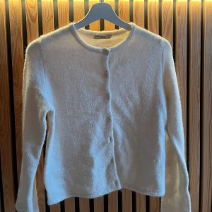 Vit kofta från Gina Tricot XS - Supermjuk och fluffig vit kofta från Gina Tricot i storlek XS. Koftan har rund halsringning, långa ärmar och knäpps med knappar framtill. Perfekt för lager-på-lager och ger en clean och mysig look.