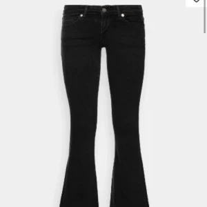 Svarta bootcut jeans med låg midja - Säljer ett par svarta bootcut jeans med låg midja och klassisk femficksdesign. Jeansen har en tight passform upptill och vida ben nertill. Materialet är stretchigt jeans, vilket gör dem bekväma och snygga till många olika looks.