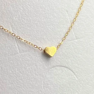 Guldigt halsband med hjärthänge - Guldplaterat sött halsband med en tunn kedja och ett litet hjärta som hänge. Perfekt för dig som gillar minimalistiska smycken med en romantisk touch. Kommer med en rosa smyckespåse. Passar till alla tillfällen när du vill addera lite extra kärlek till din outfit.