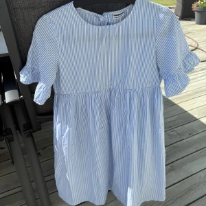 Blåvit randig sommarklänning - Jättefin kort klänning med volang ärmar, superbra skick förutom att det är ett litet hål vid en av knapparna i ryggen, går att laga🥰står ingen storlek i men passar mig bra som har xs/s💖