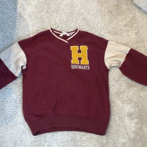  Hogwarts college-tröja - Fin Harry Potter collage tröja i mjukt bomull från H&M, har tyvärr en liten fläck som är svår att få bort.