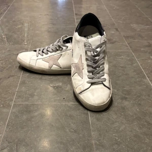 Vita Golden Goose  - Golden Goose Superstar, herr EU 44 – mycket fint skick Tidigare använda men mycket väl omhändertagna. Innersula, läderdelar och sömmar är i mycket gott skick, inga sprickor eller fläckar som påverkar utseendet.