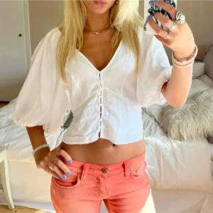Vit blus med puffärmar och knappar - Superfin vit blus med v-ringning, puffiga trekvartsärmar och knappar framtill. Croppad modell som ger en fräsch och somrig vibe. Perfekt till jeans eller kjol för en trendig look. I linnè, storlek m passar också s💗💗