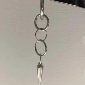 Silvrigt örhänge med kedja och spike - Coolt örhänge i silverfärg med tre ringar i kedja och en spetsig spike längst ner. Ger en edgy vibe och passar perfekt för dig som gillar minimalistiska men ändå unika smycken.