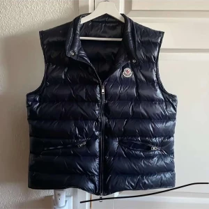 Moncler Väst - Hej säljer nu mina riktigt feta marinblåa moncler väst eftersom att den ej kommer till användning längre, den är i XL men sitter som en L,  den köptes här på Plick och jag har fått en bild på kvittot från personen jag köpte den ifrån som äkthets bevis, priset är ej hugget i sten!