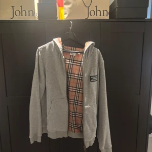 Grå Burberry hoodie med rutig insida - Säljer en Burberry hoodie i storlek M passar även S. Väldigt bra skick hör av er vid fler frågor 