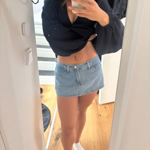 Ljusblå jeanskjol med fickor - Supersnygg ljusblå jeanskjol i kort modell med klassiska fem fickor och bälteshällor. Kjolen har dragkedja och knapp framtill och är perfekt för dig som gillar en enkel och clean stil. Obs! Det är som shorts på baksidan men en kjol framifrån