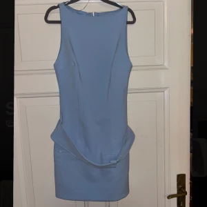 Ljusblå kort klänning från Zara - Supersnygg ljusblå kort klänning från Zara med ärmlös design och markerad midja. Klänningen har en stilren, figurnära passform och dragkedja i ryggen. Perfekt för dig som vill sticka ut med en enkel men trendig look.