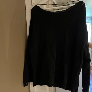 Svart stickad tröja från 157, XL - Svart stickad tröja från 157 i storlek XL. Tröjan har ett snyggt hålmönster i lodräta rader och är långärmad med en lite loose passform. Perfekt för dig som gillar enkel men stilren look.