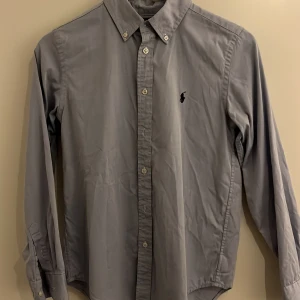 Ljusblå skjorta från Ralph Lauren! - Skön skjorta från Ralph Lauren i ljusblå färg med mörkblått emblem! Är i storlek 16 vilket är för lite mindre personer skulle säga ett den passar runt 165-170 cm lång i väldigt bra skick🙌 Bara att höra av er vid frågor🤝