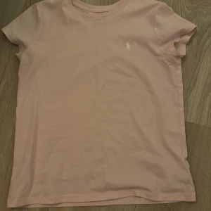 Supersöt ljusrosa t-shirt från Polo Ralph Lauren!!  - Säljer en super söt tröja från Ralph Lauren!! Använt få tal gånger så inga defekter. Säljer den för den inte passar längre!! Storlek 12-14 💗