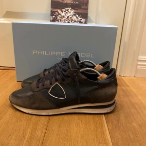 Phillipe model TRXP - Snygga svarta sneakers från Philippe Model med en stilren design. Skorna har snörning och en rund tå, vilket ger en klassisk look. Perfekta för en avslappnad stil med en touch av elegans. Skorna är i storlek 43 och boxen samt kortet ingår. Skorna är lite slitna där bak vilket man ser på bilden och därav detta riktigt bra pris. Hoppas du blir nöjd, SBstyle :)