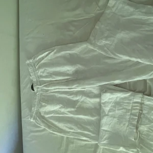 Vita linnebyxor från Lager 157, XS - Säljer ett par vita linnebyxor från Lagrr 157 i storlek XS. Byxorna har resår i midjan för extra komfort och är tillverkade i ett lätt och luftigt linnematerial. Perfekta för varma dagar när du vill ha en chill och stilren look. Säljer då jag har ett par andra som används mer.