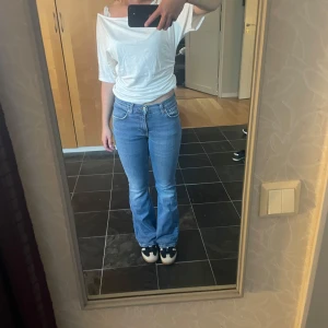 Low/mid waist bootcut jeans - Ljusblå low/mid waist bootcut jeans från Gina tricot storlek 34 i bra skick! Stretchigt material (98% Bomull, 2% Elastan)  Mått (kan skilja sig ngn cm): Midja rakt över: 34 cm (stretch!) Midjehöjd: 21 cm  Innerbenslängd: 76 cm