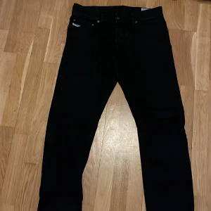 Diesel Svarta jeans med slim fit - Snygga svarta jeans med klassisk femficksdesign och smal passform. Byxorna har normal midja och raka ben, perfekta till sneakers eller boots. Materialet är jeans och färgen är helt svart, vilket gör dem enkla att matcha med allt.