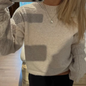 Beige stickad tröja  - Supermysig beige stickad tröja från Bubbleroom i storlek XS. Tröjan har grov ribbad kant vid hals, ärmslut och nederkant samt snygga kabelstickade detaljer på ärmarna. 