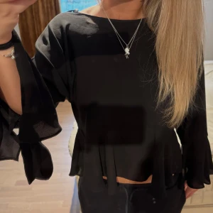 Svart blus med volangärm från Zara - Supersnygg svart blus från Zara Trafaluc med volangdetaljer nertill och på ärmarna. Långa ärmar med knytband vid handleden och en söt rosett i nacken. 💞💞🤗🤗
