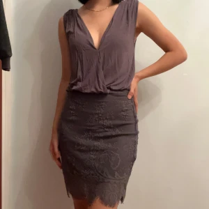 Snygg och skön spetsklänning  - Supersnygg grå kortklänning från Oneness med djup v-ringning och omlott. Sitter väldigt bekvämt och snyggt. Har en knapp vid urringningen som syns i sista bilden. Perfekt för dig som gillar stilrena och feminina plagg med det lilla extra. Säljs då den är lite för stor för mig!