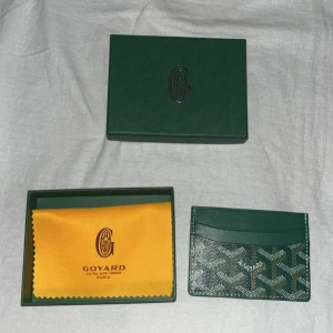 G plånbok  - Snygg och stilren i grön  med deras ikoniska mönster. Plånboken har flera kortfack och är tillverkad i skinn med tryckt logga framtill. Perfekt för dig som vill ha något exklusivt och smidigt i fickan.  