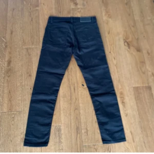 Svarta skinny jeans tigerofsweden  - Snygga svarta jeans med fem fickor och smal passform. Klassisk design med knapp och dragkedja framtill. Perfekta för dig som gillar en stilren look och vill ha ett par tajta jeans som sitter snyggt hela vägen ner.