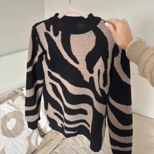 Stickad tröja - Säljer en stickad tröja från Object i storlek XS med svart och beige zebramönster. Använd fåtal gånger. Materialet är mjukt och skönt mot huden.