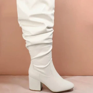 Vita höga boots med blockklack - vita boots med högt skaft och rynkad design. Skorna har en stabil blockklack och rund tå, tillverkade i syntetmaterial med en slät finish. 