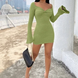 Grön kortklänning  - Supersnygg grön kortklänning från SHEIN med långärmade trumpetärmar och twistad detalj vid bysten. Klänningen har en figurnära passform och är tillverkad i mjukt stretchigt material.