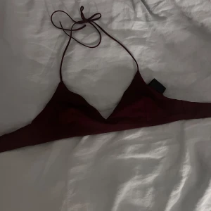 Vinröd bikiniöverdel - Snygg vinröd bikiniöverdel med trekantsform och smala axelband. Stängs med spänne i ryggen. Enkel och stilren design, perfekt för stranden eller poolen.