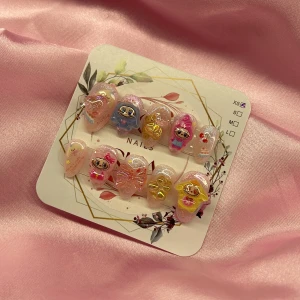 ChiChi(XS);Short Almond - Supergulliga gelé press-on naglar i rosa med glitter, 3D-bågar och färgglada figurer. Mix av motiv i blått, gult och rosa, dekorerade med små stjärnor och hjärtan. Naglarna har en kort mandel form och kommer i storlek   XS: 14 mm, 11 mm, 11,5 mm, 10 mm, 8 mm .  Perfekt för dig som vill ha unika och lekfulla naglar.
