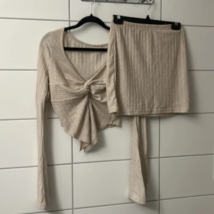 Beige ribbad kortkjol med matchande topp - Superfin beige ribbad kortkjol med elastisk midja. Kjolen har en enkel och clean look som är lätt att matcha med olika toppar. Perfekt för dig som gillar en stilren och trendig vibe.