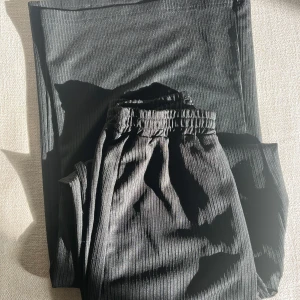 Svarta ribbade mjukisbyxor - Säljer ett par svarta mjukisbyxor med ribbad struktur och resår i midjan. Byxorna har en relaxed fit och är perfekta för chill dagar. Materialet känns mjukt och stretchigt, vilket gör dem riktigt sköna att ha på sig.