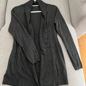 Mörkgrå kofta från Esmara, storlek S. - Mysig och stilren mörkgrå kofta från Esmara. Koftan är öppen framtill med bred ribbad kant och har långa ärmar. Perfekt att slänga på sig över en t-shirt eller topp för en chill och enkel look.