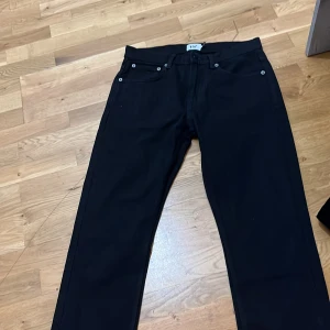 Svarta jeans från 157, straight fit - Svarta jeans från 157 med klassisk femficksdesign och raka ben. Jeansen har silverfärgade nitar och bälteshällor. Materialet är bomull med en skön känsla och passformen är normal. Perfekta för dig som gillar stilrena och enkla jeans.