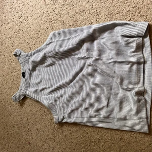 Blåvit linne - Snygg ärmlös linnetopp i blått och vitt med randigt mönster. rak passform, perfekt till jeans eller kjol. Tunt och svalt material som passar bra till varmare dagar.