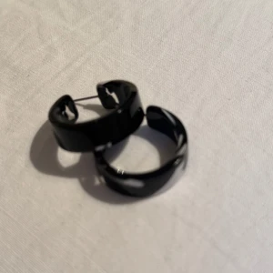 Svarta chunky hoops örhängen - Säljer ett par svarta chunky hoops örhängen med blank finish. De är runda och har en stilren, modern look som passar perfekt till en edgy outfit.