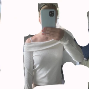 Vit offshoulder tröja från BikBok - Säljer en stilren vit offshoulder tröja från BikBok. Toppen är ribbad, har lång ärm och sitter snyggt över axlarna. Perfekt för dig som gillar en enkel men trendig look. Materialet är mjukt och stretchigt för en bekväm passform.