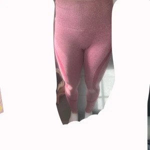 Rosa tights med hög midja - Säljer ett par rosa tights med hög midja och snygga detaljer längs benen. De är stretchiga och sitter skönt och tight, perfekta för gymmet eller chill. Materialet är mjukt och följsamt, och färgen är en ljusrosa ton med mönstrade partier. Använda några gånger🩷