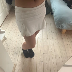 Vit kortkjol från Nike i S - Superfräsch vit kortkjol från Nike med diskret logga framtill. Kjolen har en sportig look med små slitsar i sidorna och är gjord i ett mjukt och stretchigt material som passar perfekt till tennis eller träning. (Är en tennis kjol)