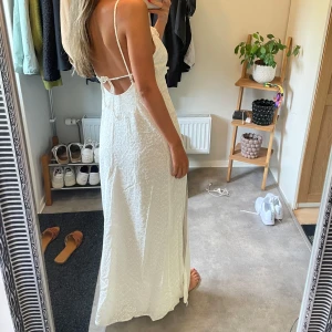 Vit långklänning med broderade blommor - Säljer en superfin vit långklänning med tunna axelband, öppen rygg.