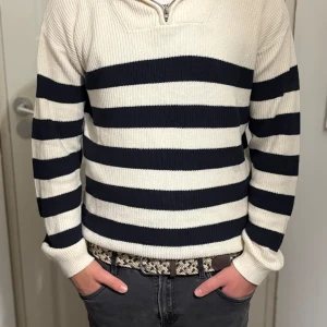 stickad half zip-tröja - Säljer en stickad tröja från H&M med svarta och vita ränder. Tröjan har en half zip-dragkedja vid halsen och är långärmad. Jätte fint skick och knappt använd.