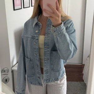 Oversized jeansjacka från Zara - Snygg oversized jeansjacka från Zara i ljusblå denim. Jackan har stora fickor framtill, krage och knäppning med knappar. 