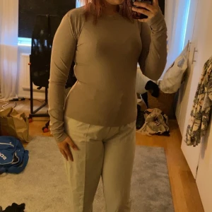 Beige ribbad långärmad tröja - Säljer en beige långärmad tröja i ribbat material. Tröjan har en tight passform och rund halsringning, perfekt att styla med jeans eller kjol. Enkel och stilren design som funkar året runt.
