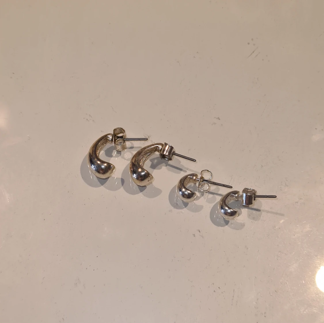 Två par silvriga örhängen i chunky design