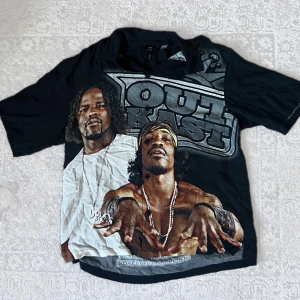 Svart Outkast t-shirt från H&M - Cool svart t-shirt från H&M med stort tryck av Outkast på framsidan och låtlista på baksidan. Perfekt för musikälskare som vill ha en avslappnad stil. T-shirten har en loose fit och korta ärmar.