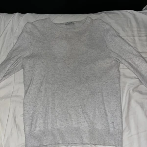 Stilgruvan stickad tröja - Säljer en stilren grå stickad tröja från Stilgruvan som är Oliver Kastells företag som lagts ner. Tröjan har långa ärmar och ribbstickade muddar vid ärmslut och nederkant. Storlek S.