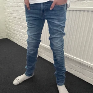 Replay anbass jeans - Snygga blå jeans från Replay med en klassisk femficksdesign och lätt slitna detaljer. De har en normal passform och är perfekta för en avslappnad stil. Märkeslogga på bakfickan och en bekväm midwaist. Storlek är 30/34