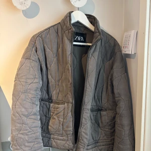 Grå quiltad jacka från Zara - Säljer en grå quiltad jacka från Zara med dragkedja framtill. Jackan är i super bra skick och i storlek S. Nypris 900kr och säljer för 400kr. 